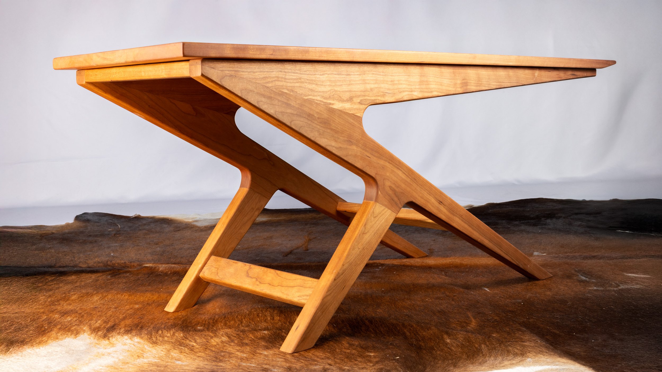 A wooden, modern-style table with angular legs.