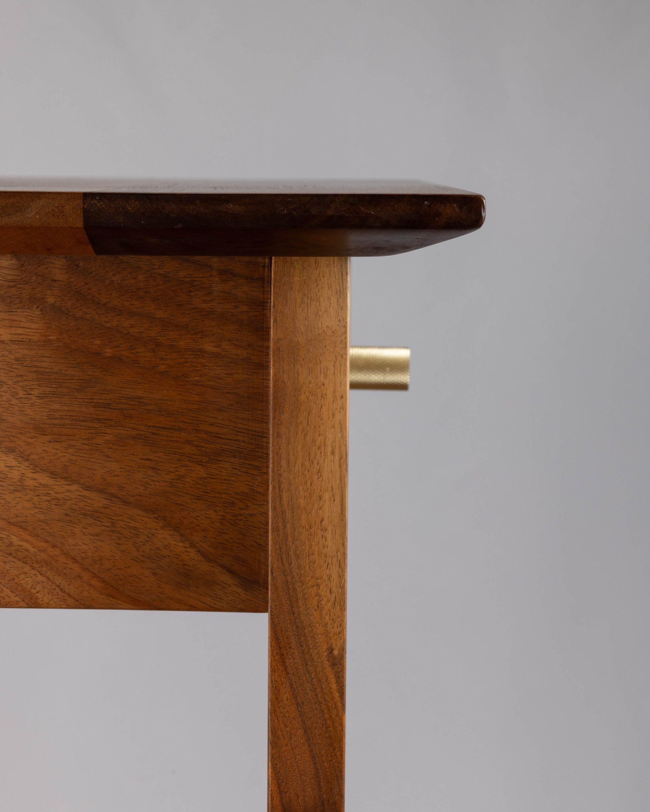 Close-up of vintage wooden furniture corner with brass pull handle.