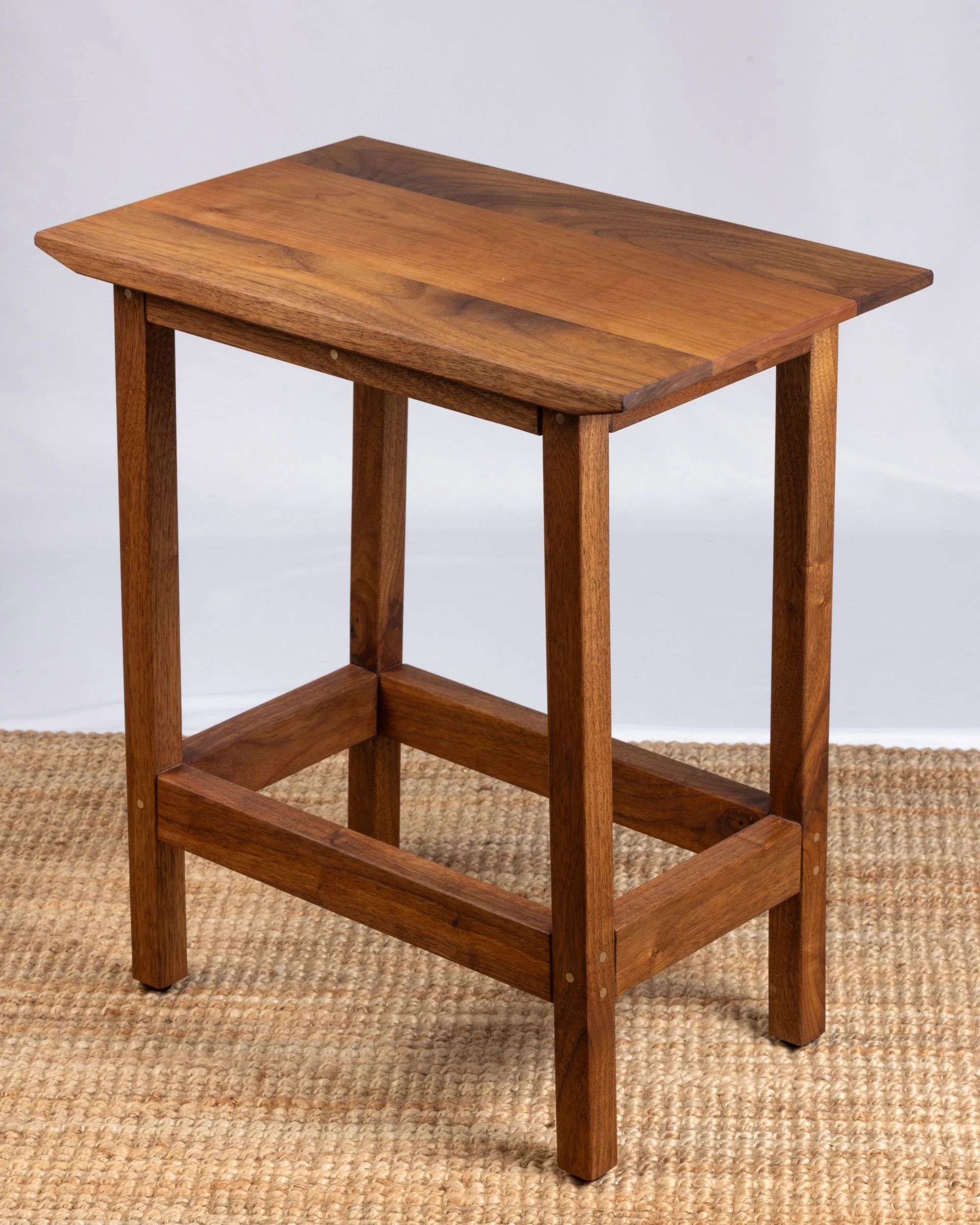 A small wooden side table with four legs and a lower support.