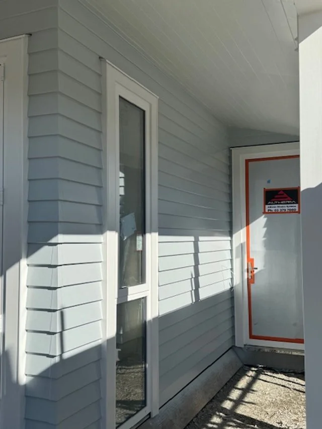 View of a building's exterior wall with a glass door and a door labeled 'Authorized Personnel Only' in a red frame.