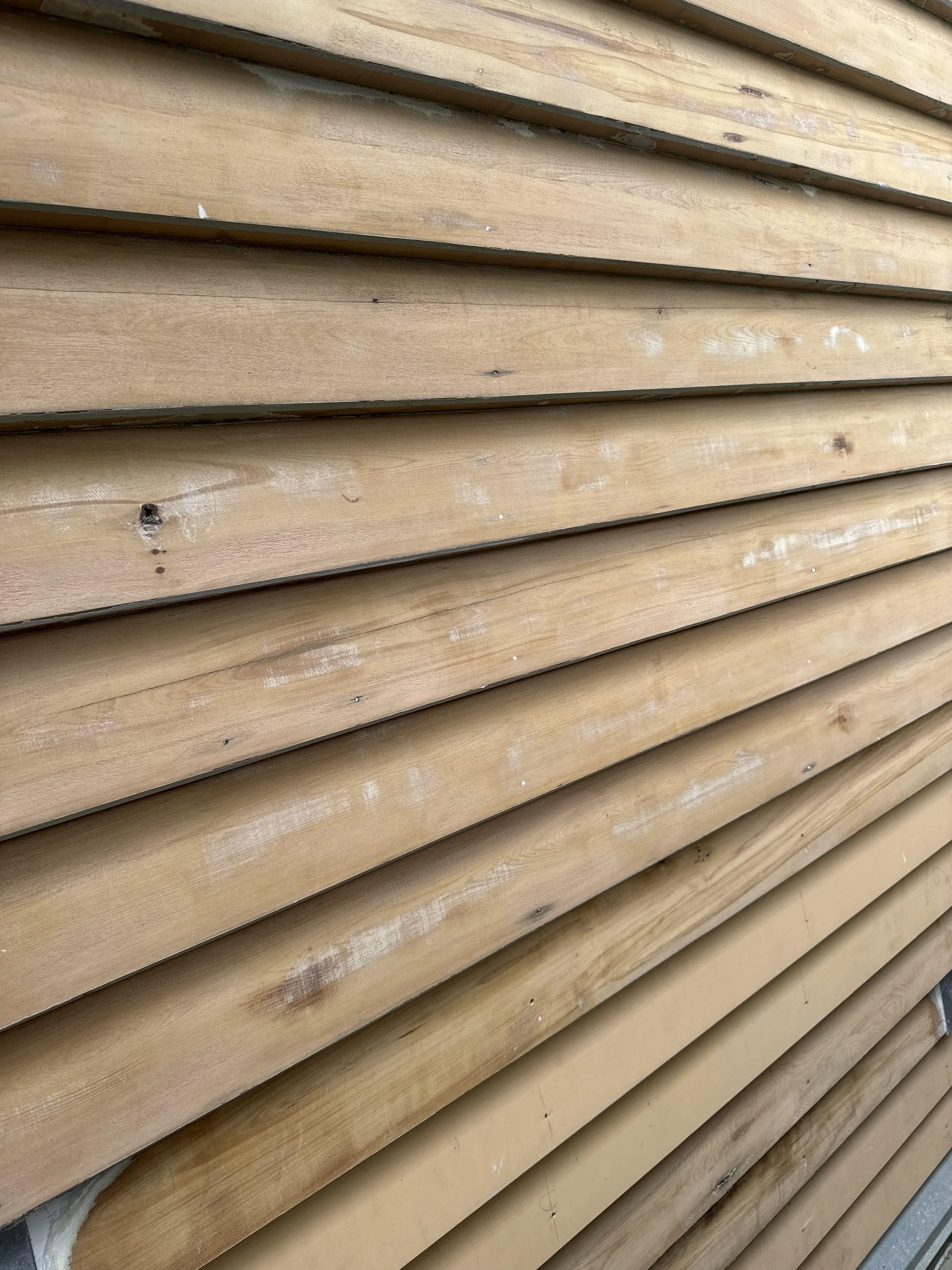 Close-up of horizontal wooden siding on a building, showing natural wood grain and knots.