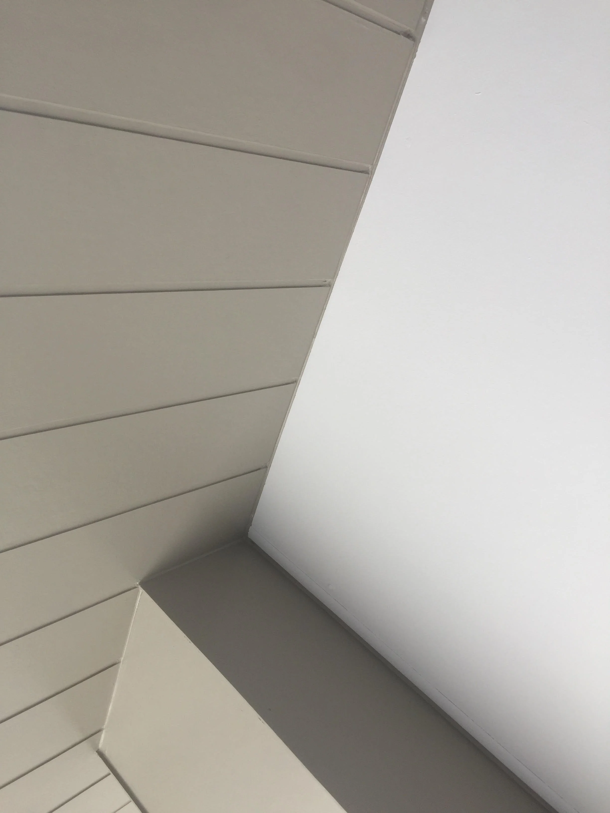 Ceiling corner with wooden paneling and white roof.