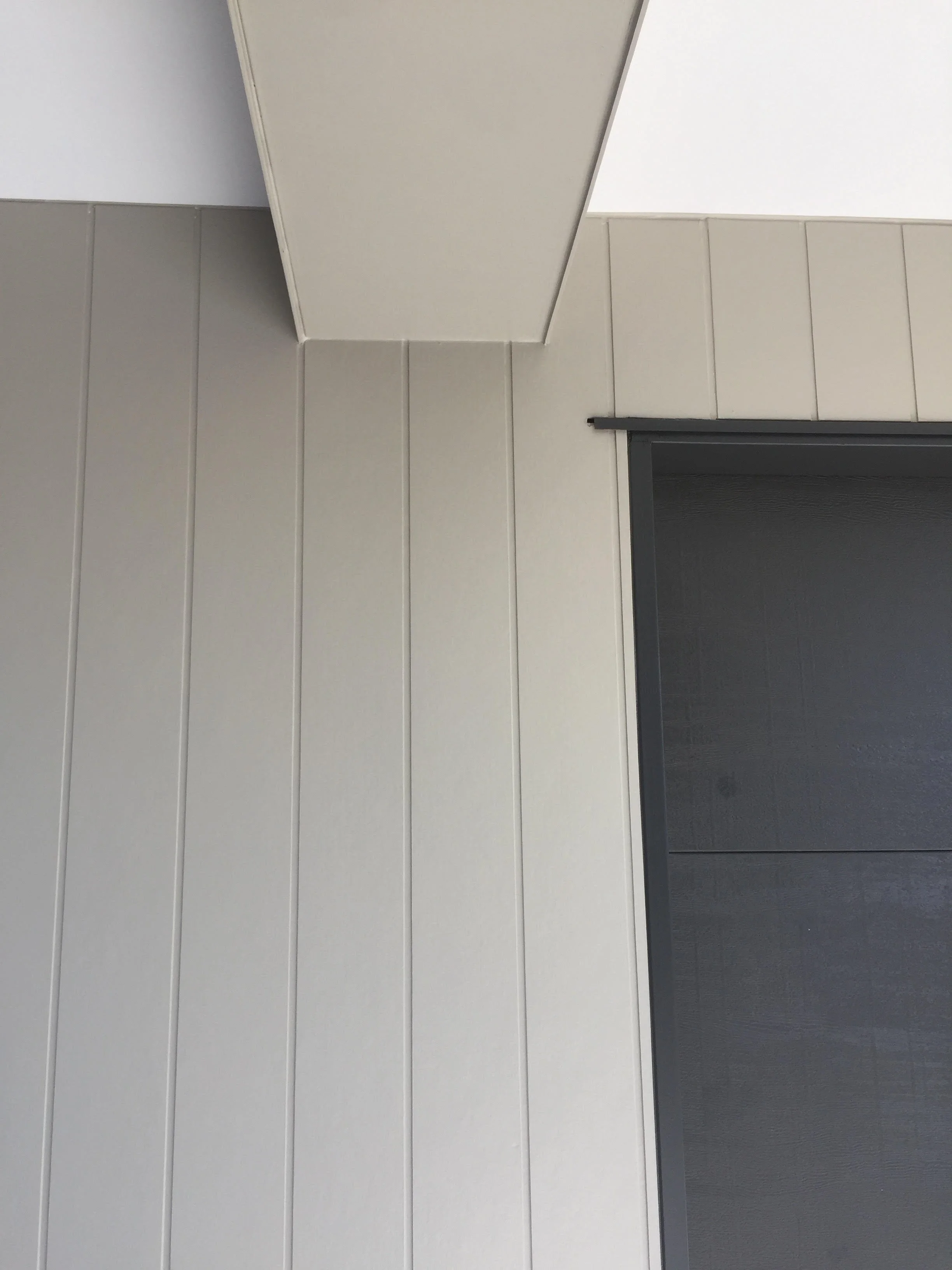 Close-up of cream-colored wall panels, corner of ceiling, and a black door or window frame.