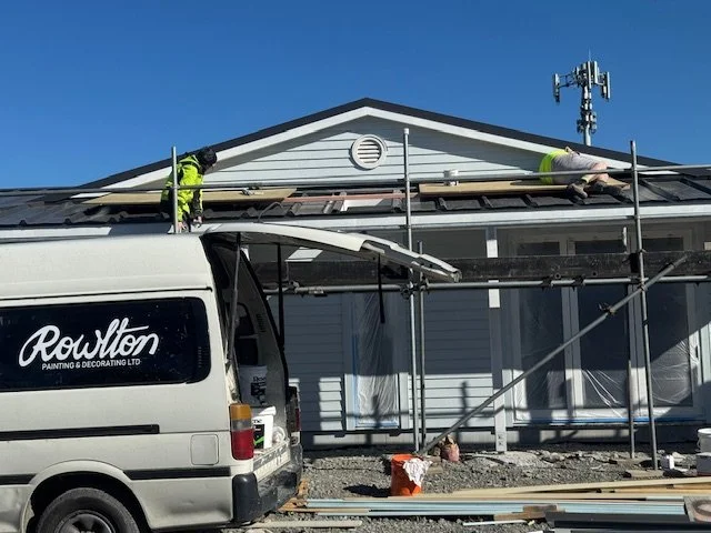 Construction workers repairing the roof of a house with a ladder and scaffolding.