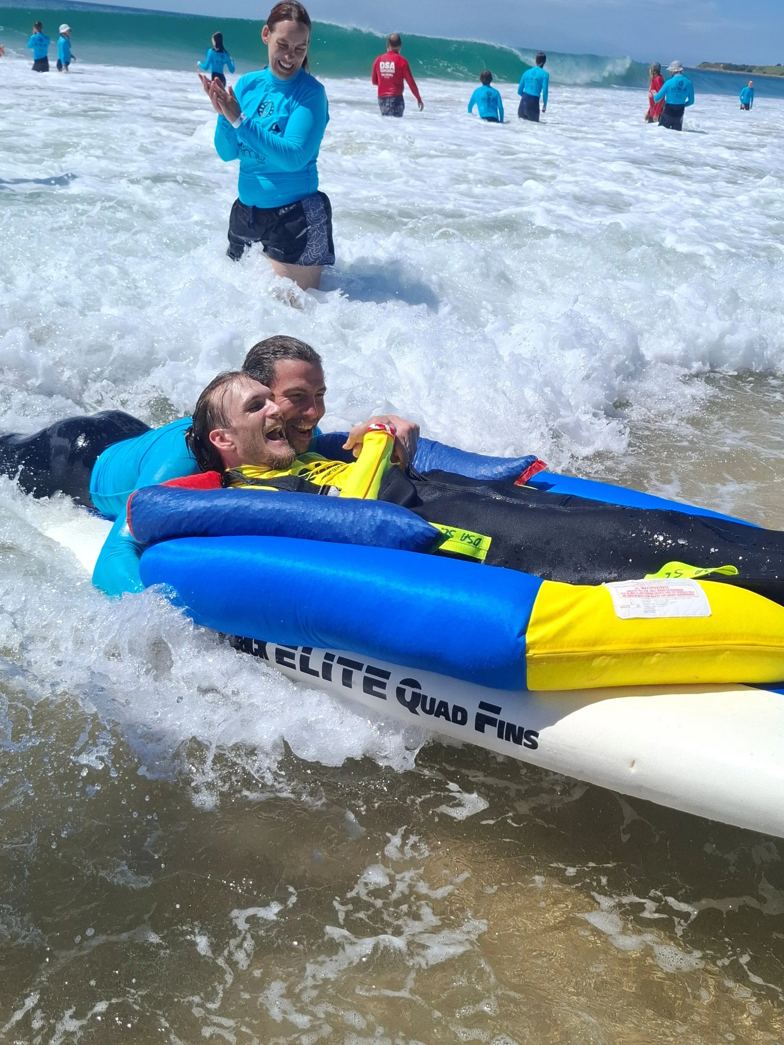 Man with disability surfing with the assistance of DSA