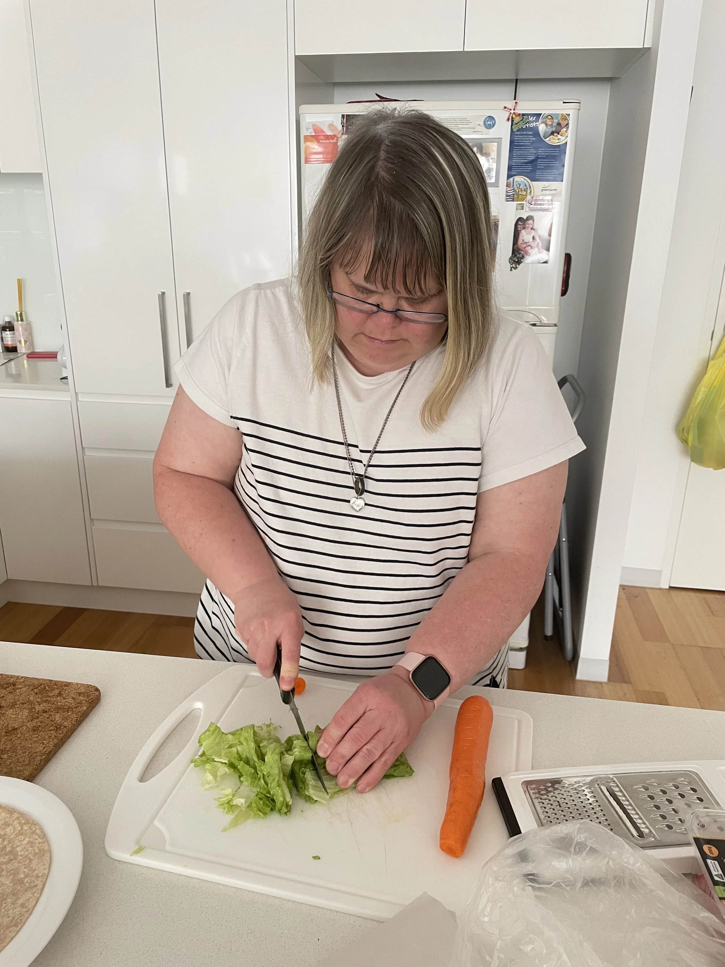 A woman cutting up a salad on a chopping board