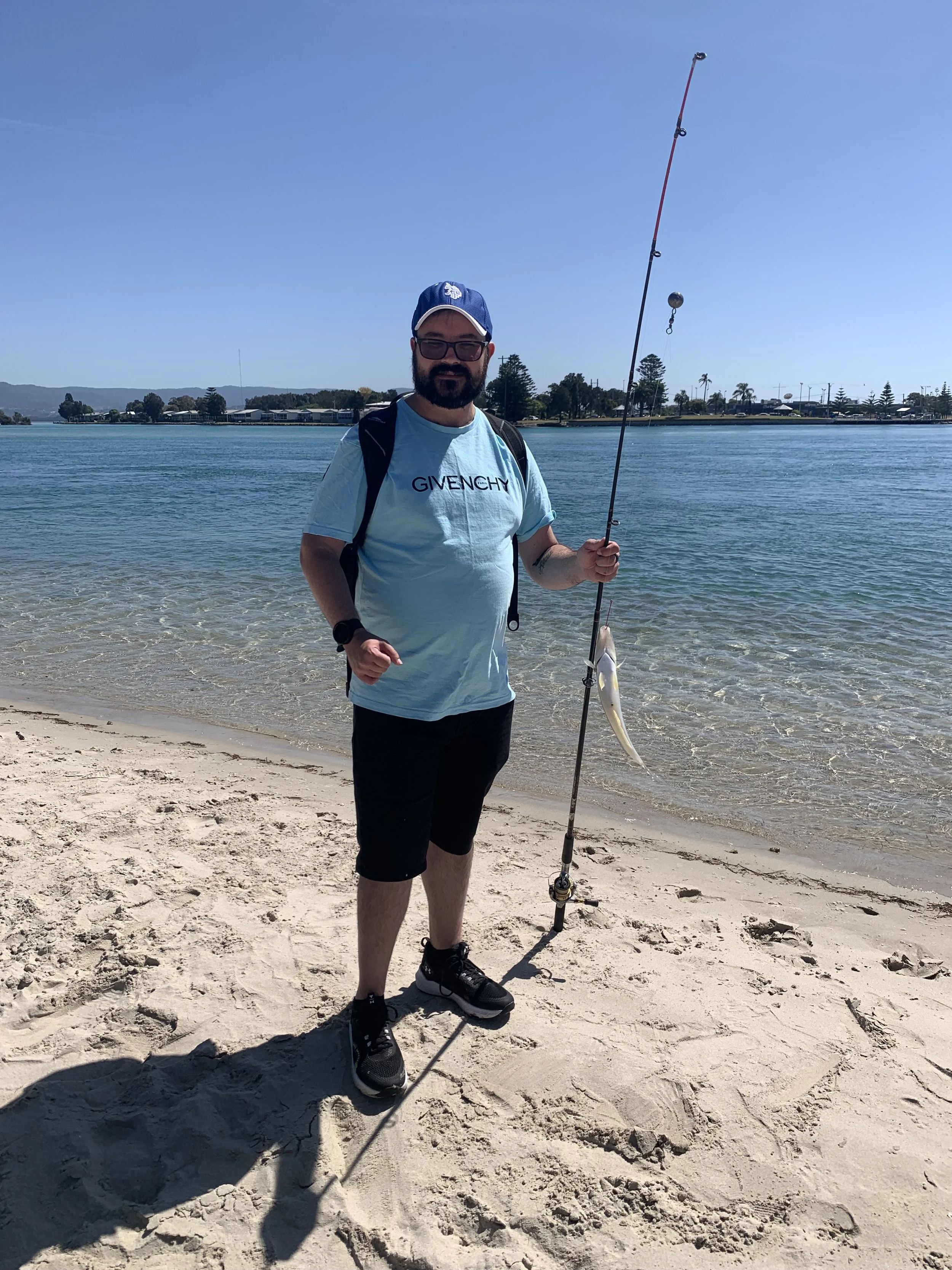 A participant standing with a fish on a fishing rod next to water at Windang
