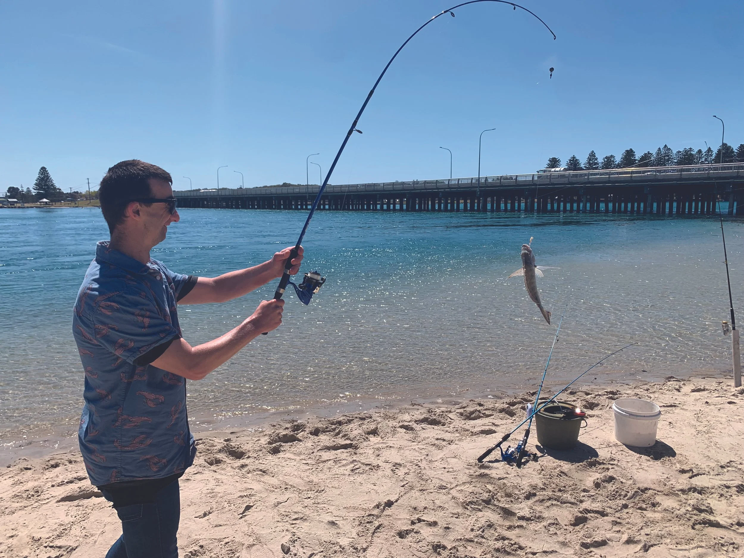 A man fishing at Lake Illawarra with a fish on the line