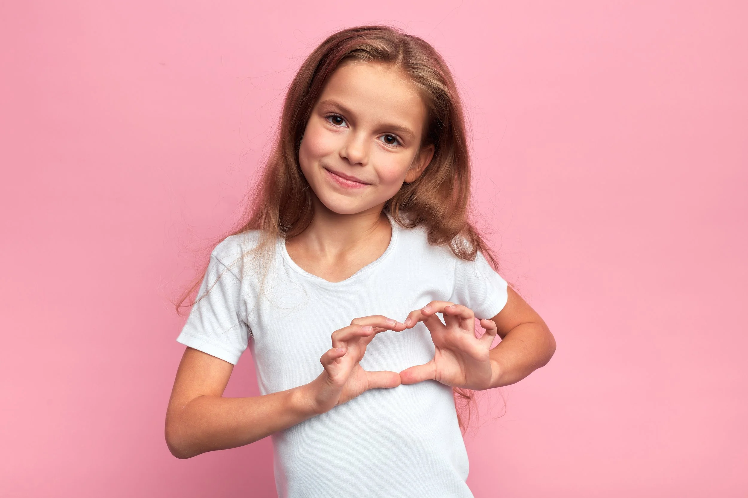 Little girl doing Auslan sign with pink background