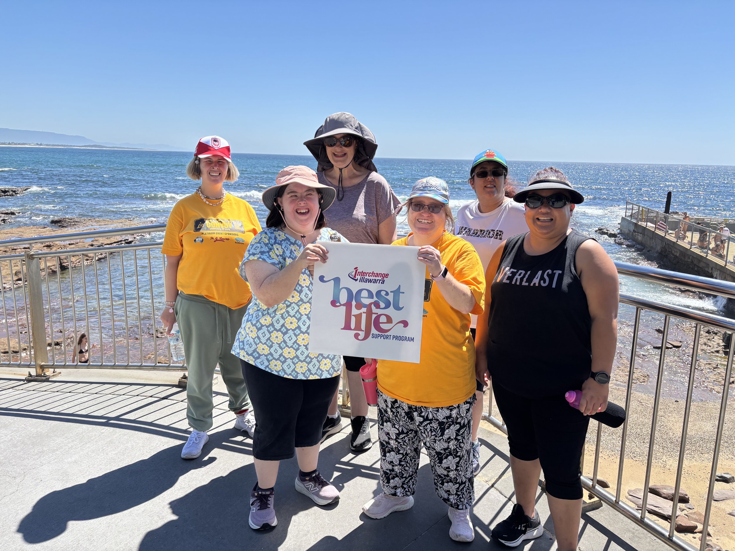 Participants holding the BestLife sign next to the water at North Wollongong