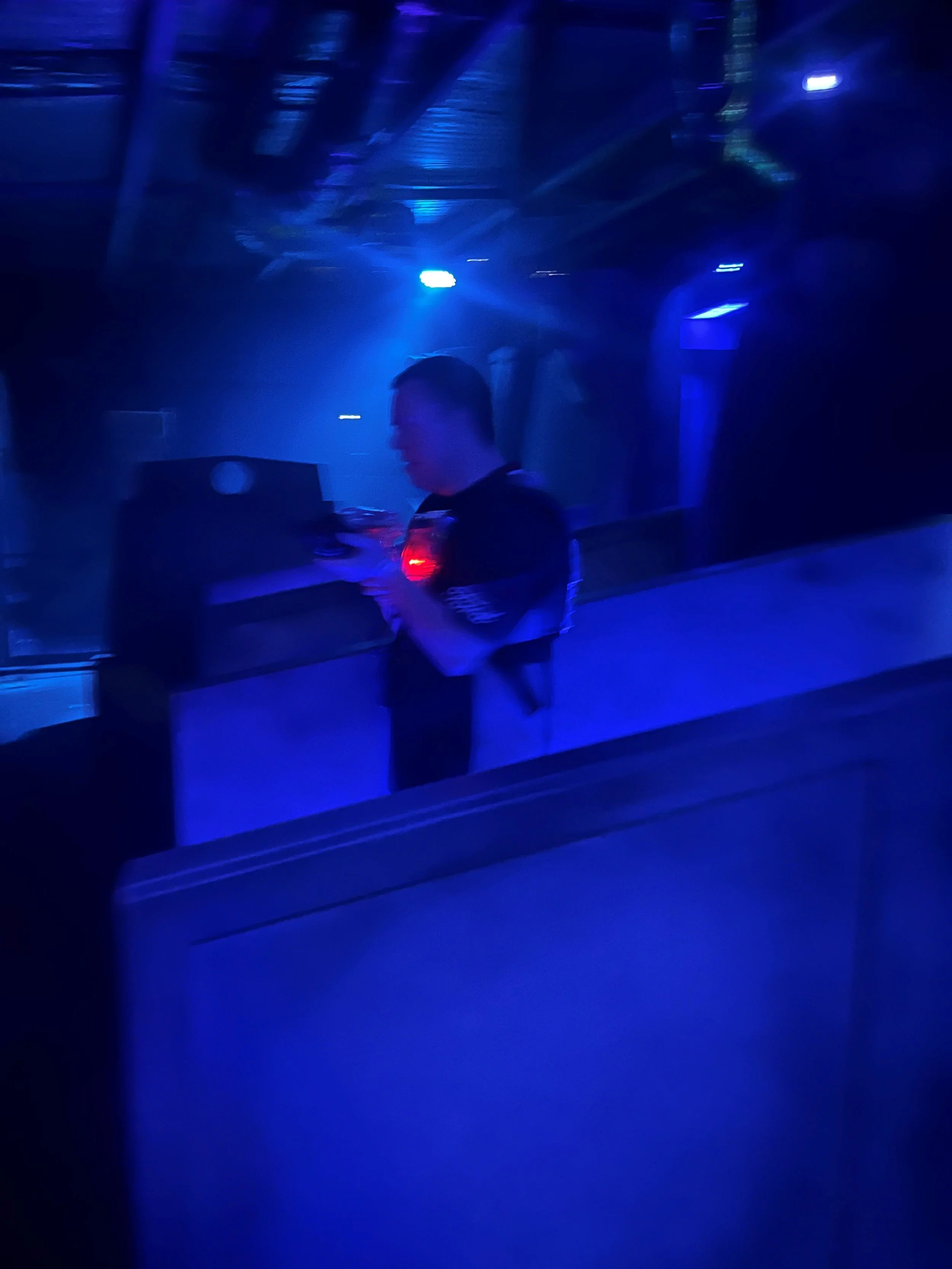 A young man doing laser tag in a dark blue lit room