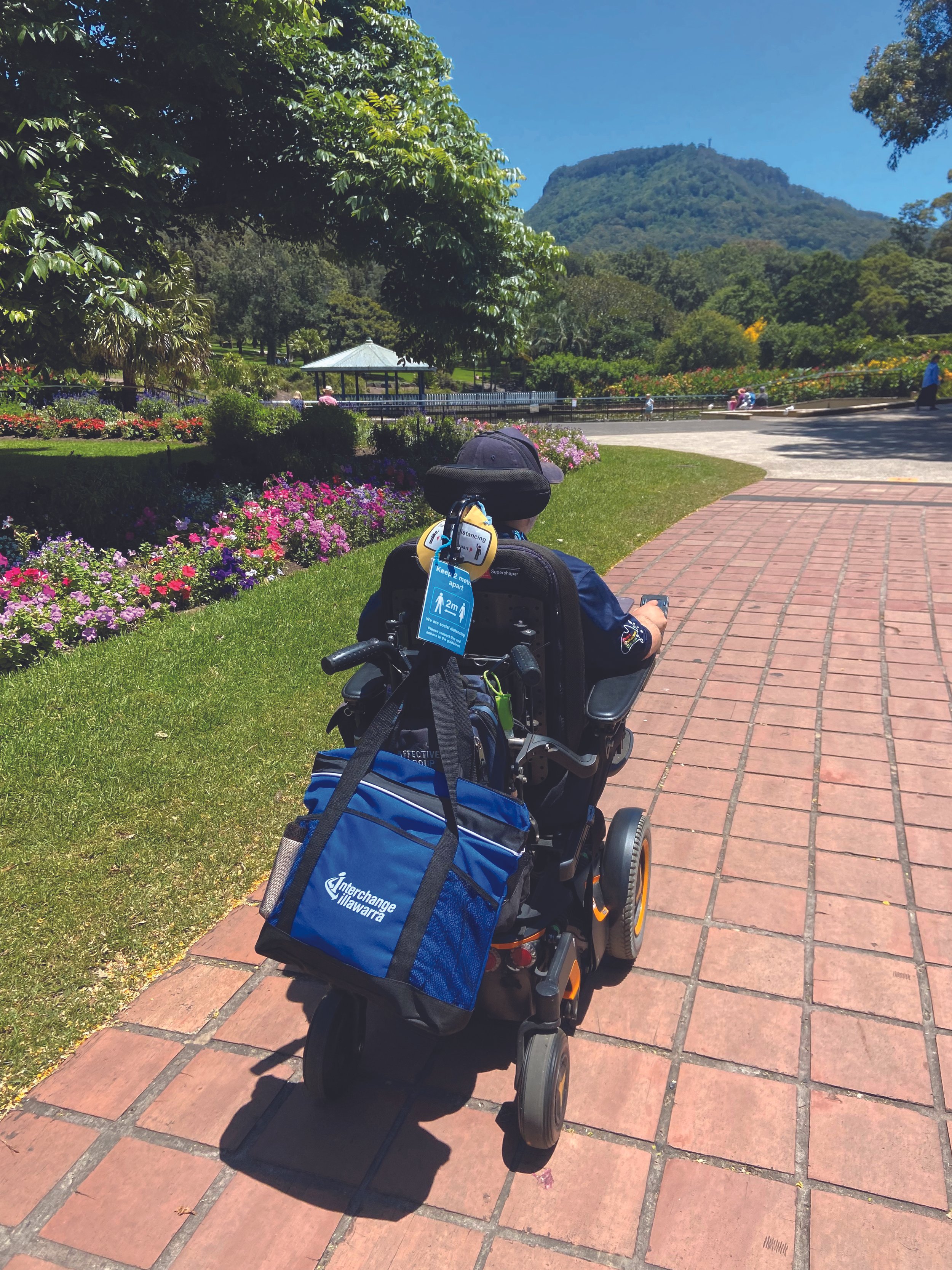 Man in power wheelchair on path at the Botanic Gardens in Wollongong