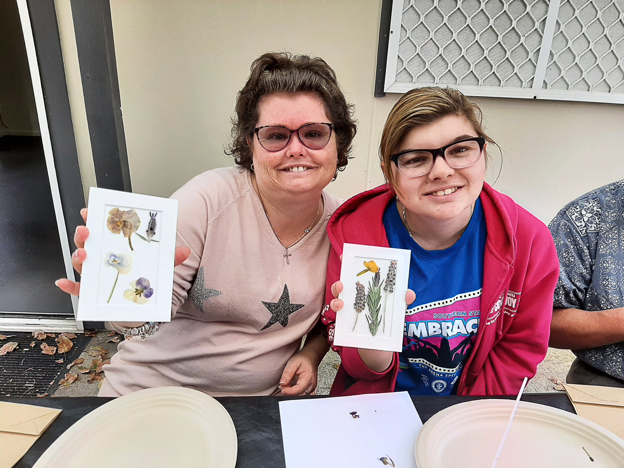Participants proudly showing the pressed flower cards they have made