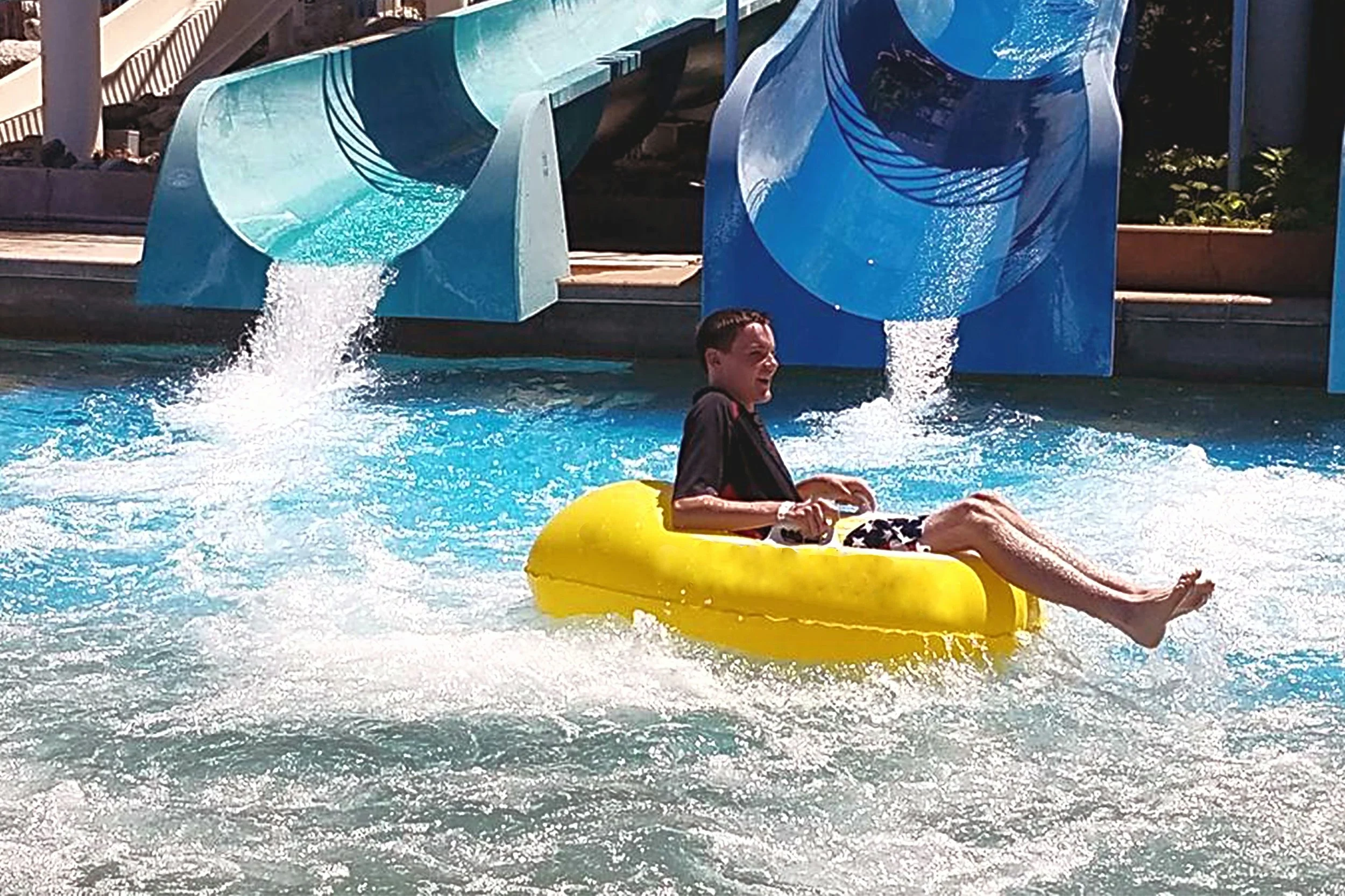 Participant at a water park on a yellow float at the base of a waterslide