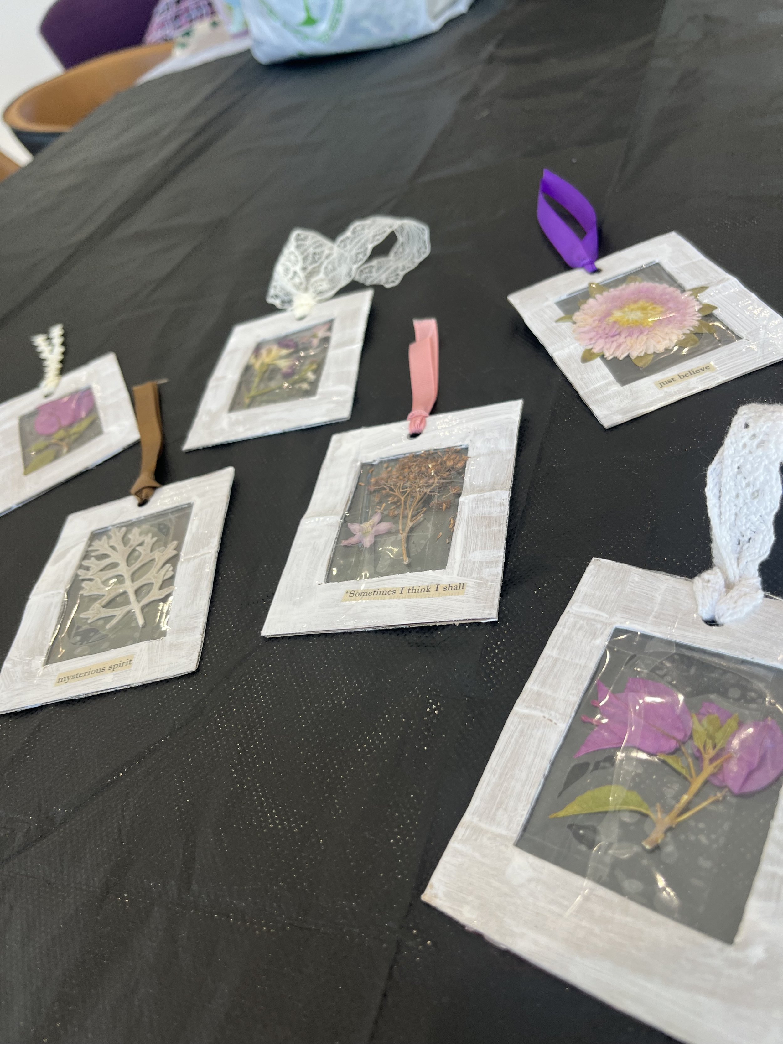 A photo of pressed flowers in frames with ribbons at the top