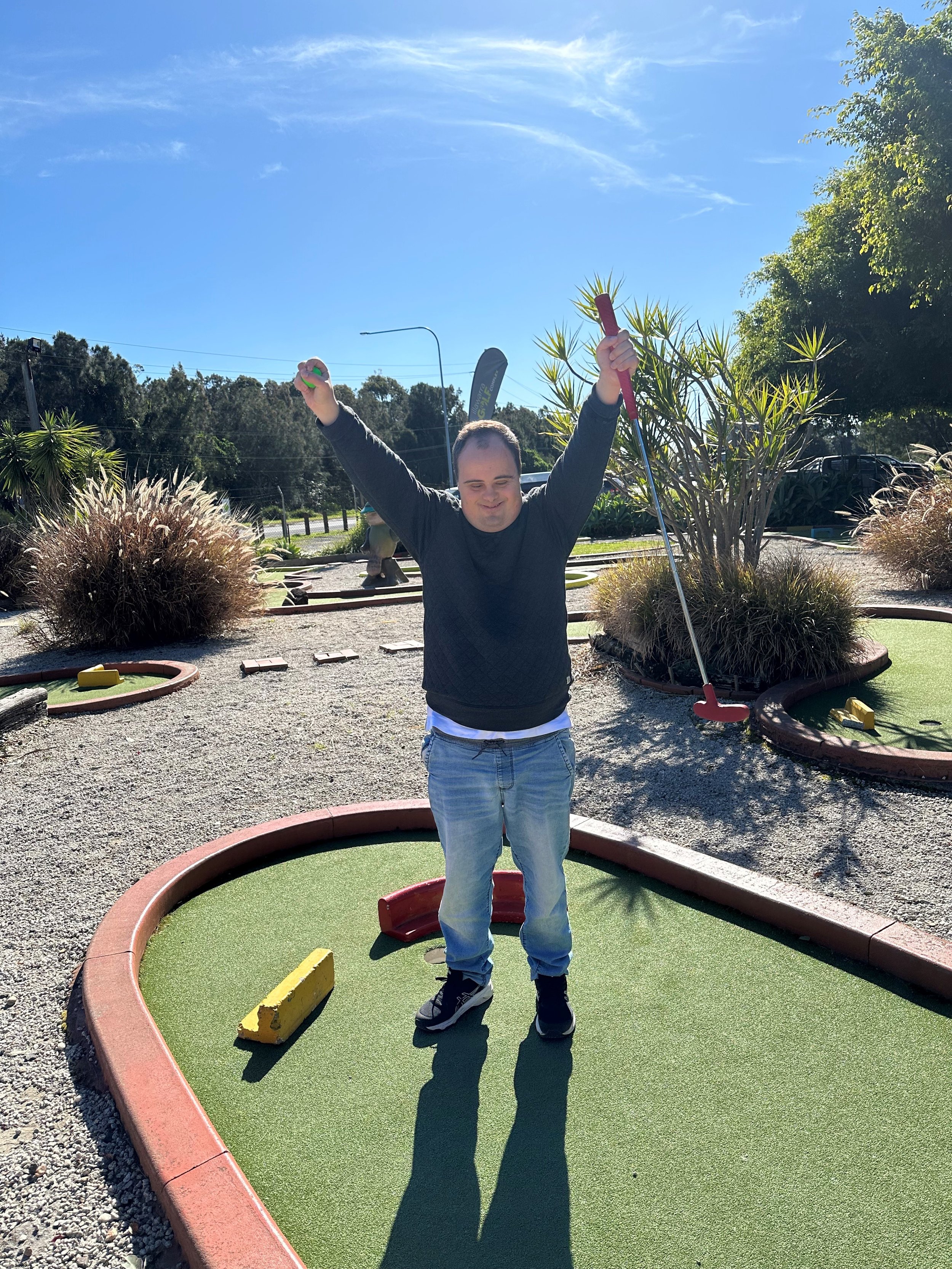 A man with a golf club celebrating a putt putt great shot