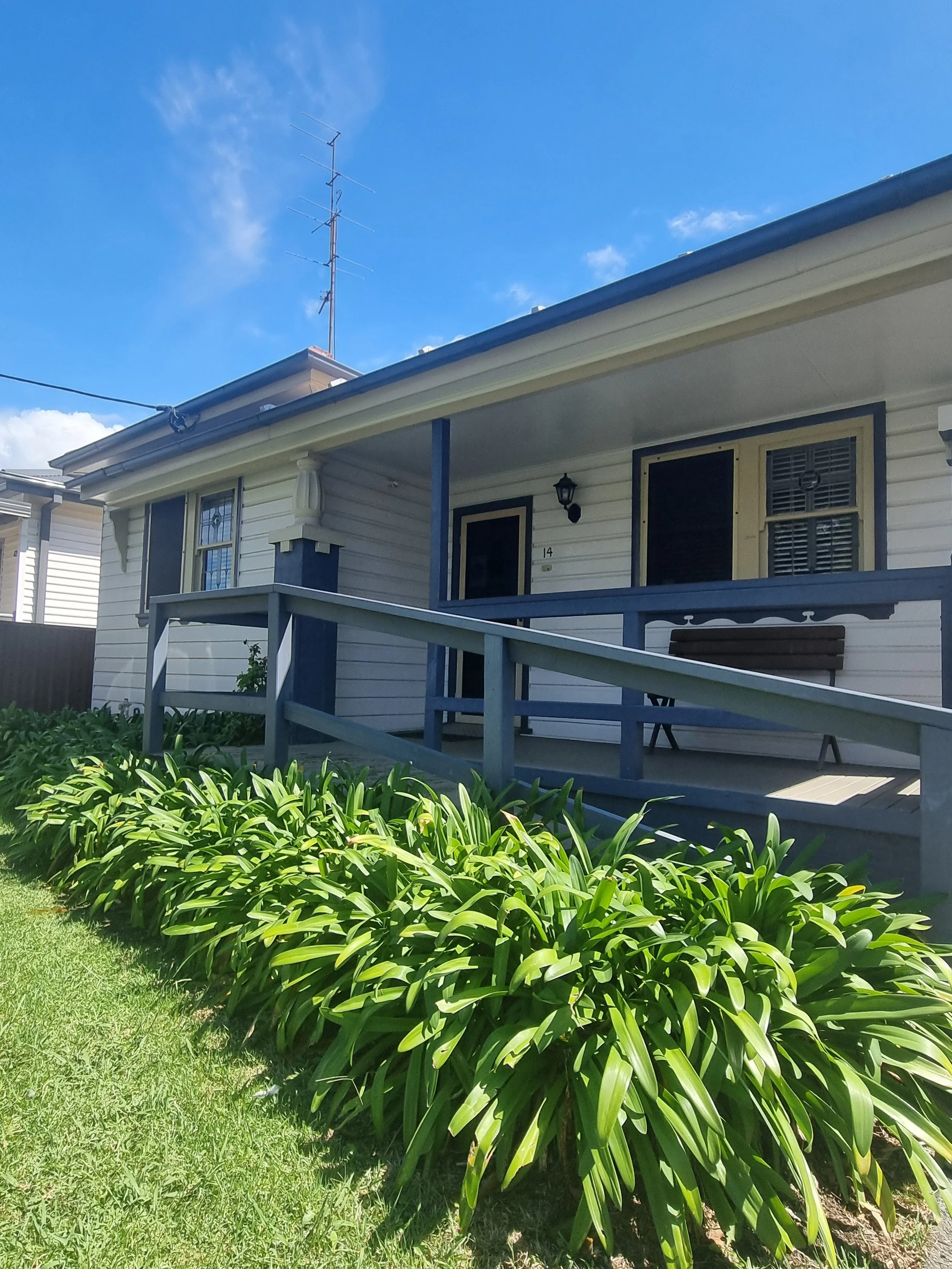 Photo of the cottage at Evans Street featureing cream weatherboard, ramp and green garden