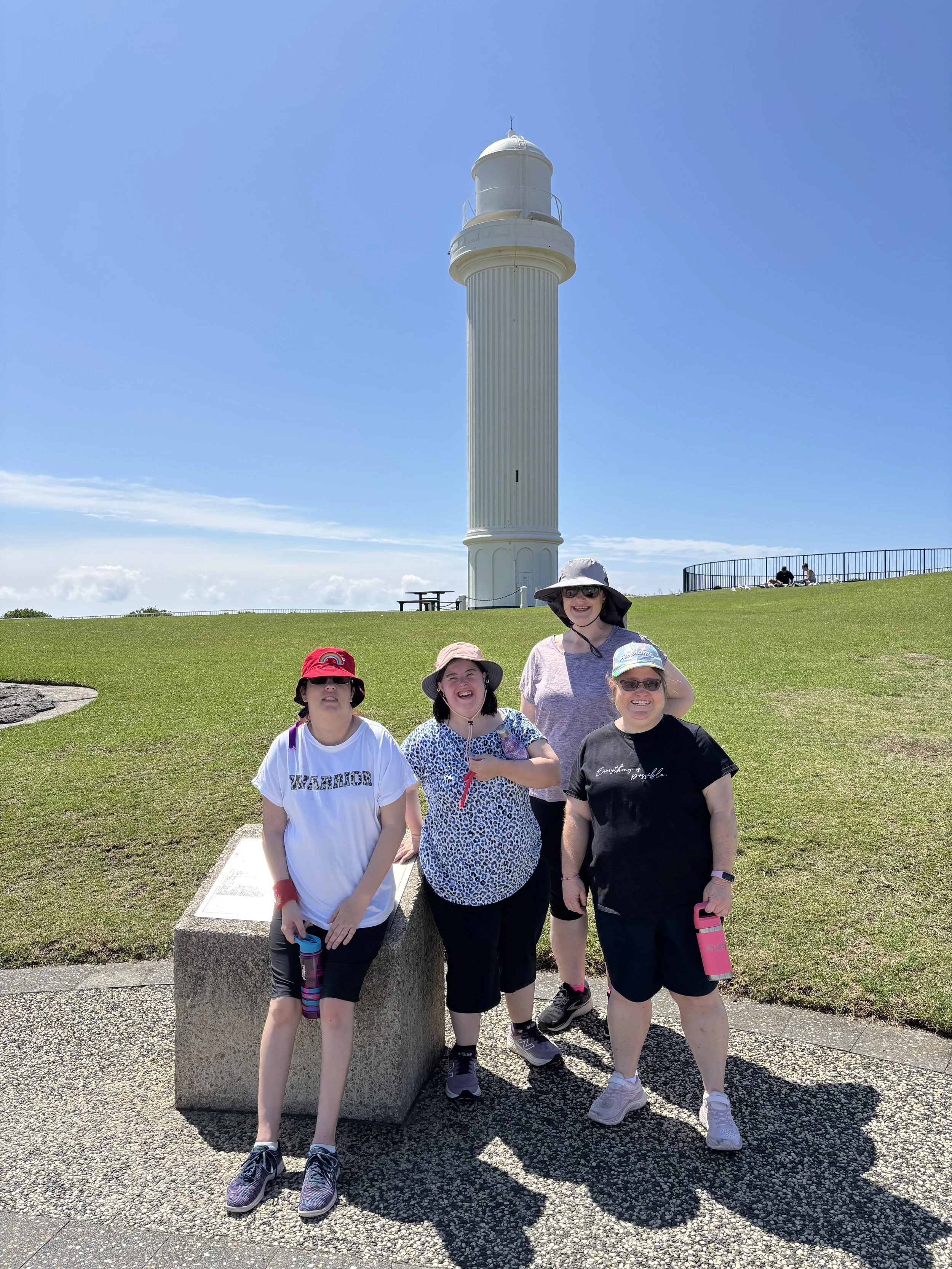 A group of women in front of a lighthouse