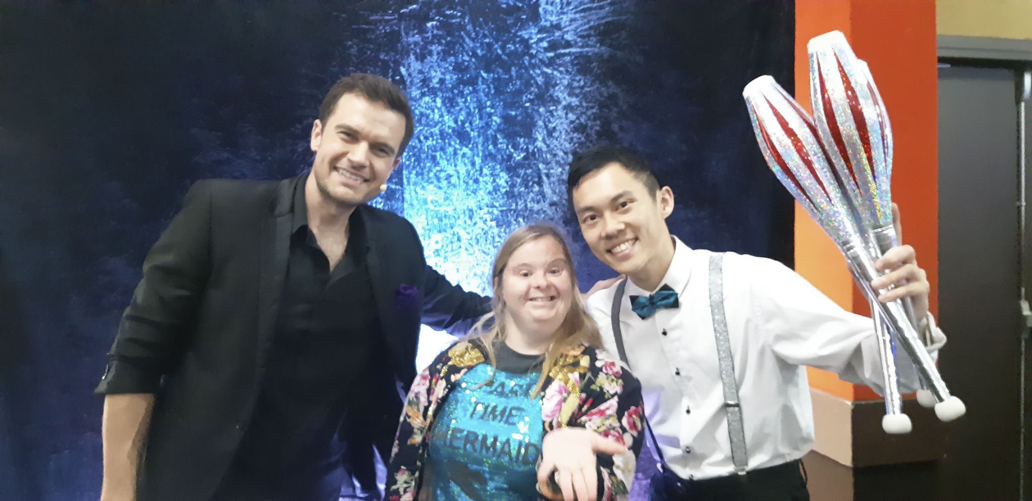 Participant at a magic show with host and magician