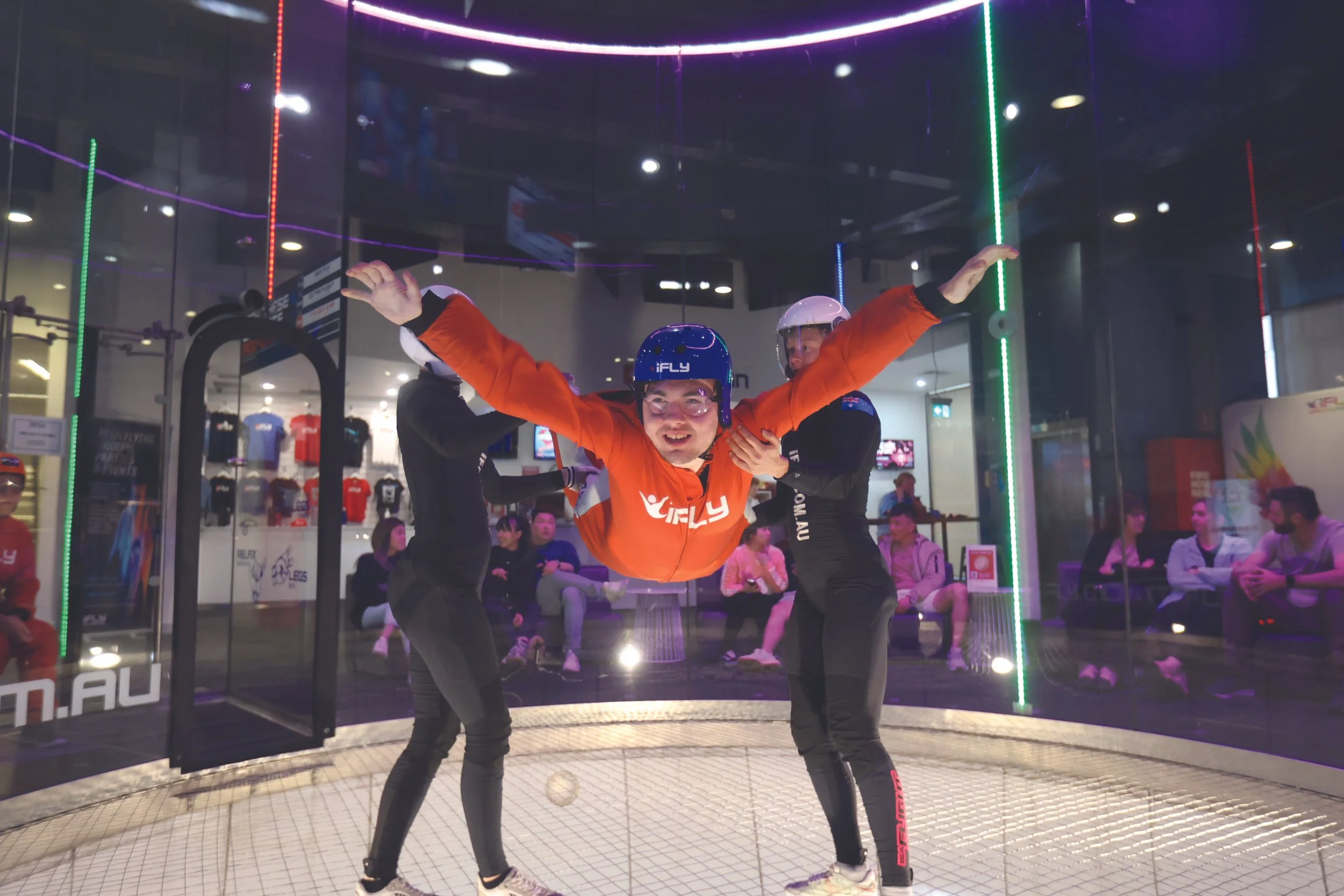 Male participant at ifly, doing indoor sky diving in an orange jumpsuit