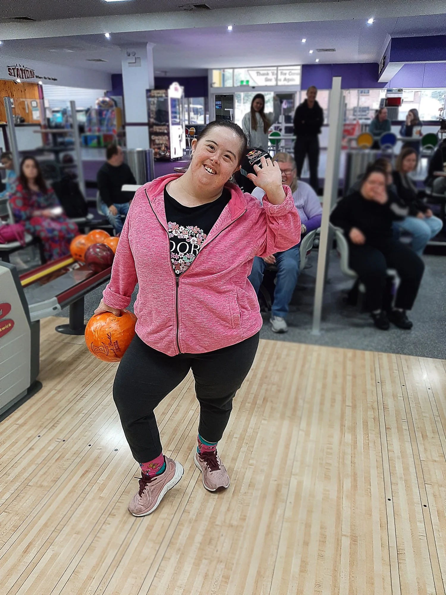 Woman in a pink top holding onto a bowling ball