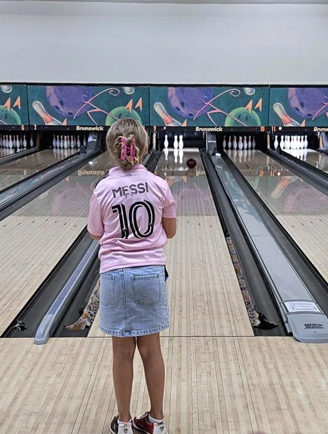 Young girl at bowling alley in pink t-shirt
