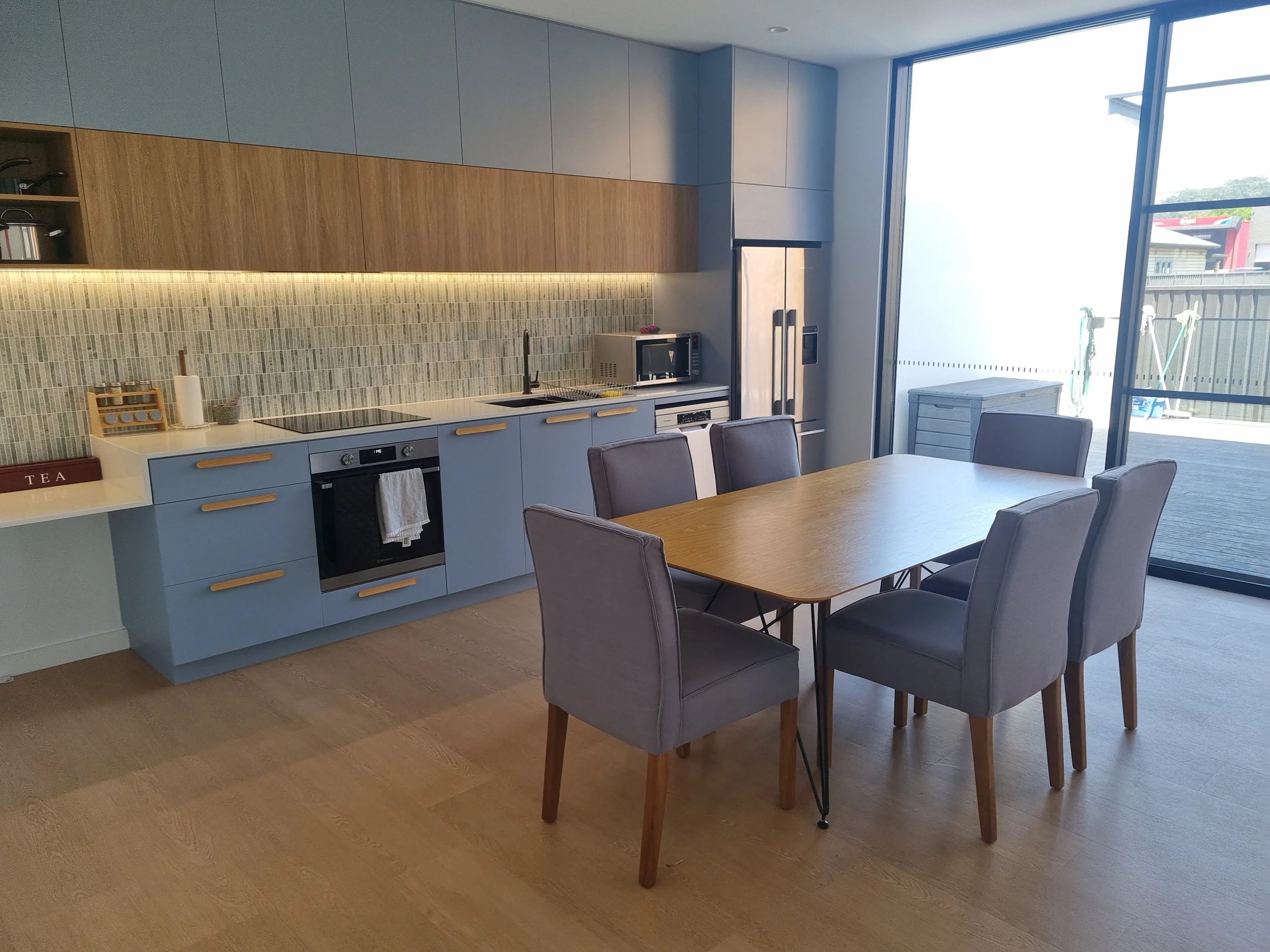New accessible kitchen with blue cupboards and a dining table