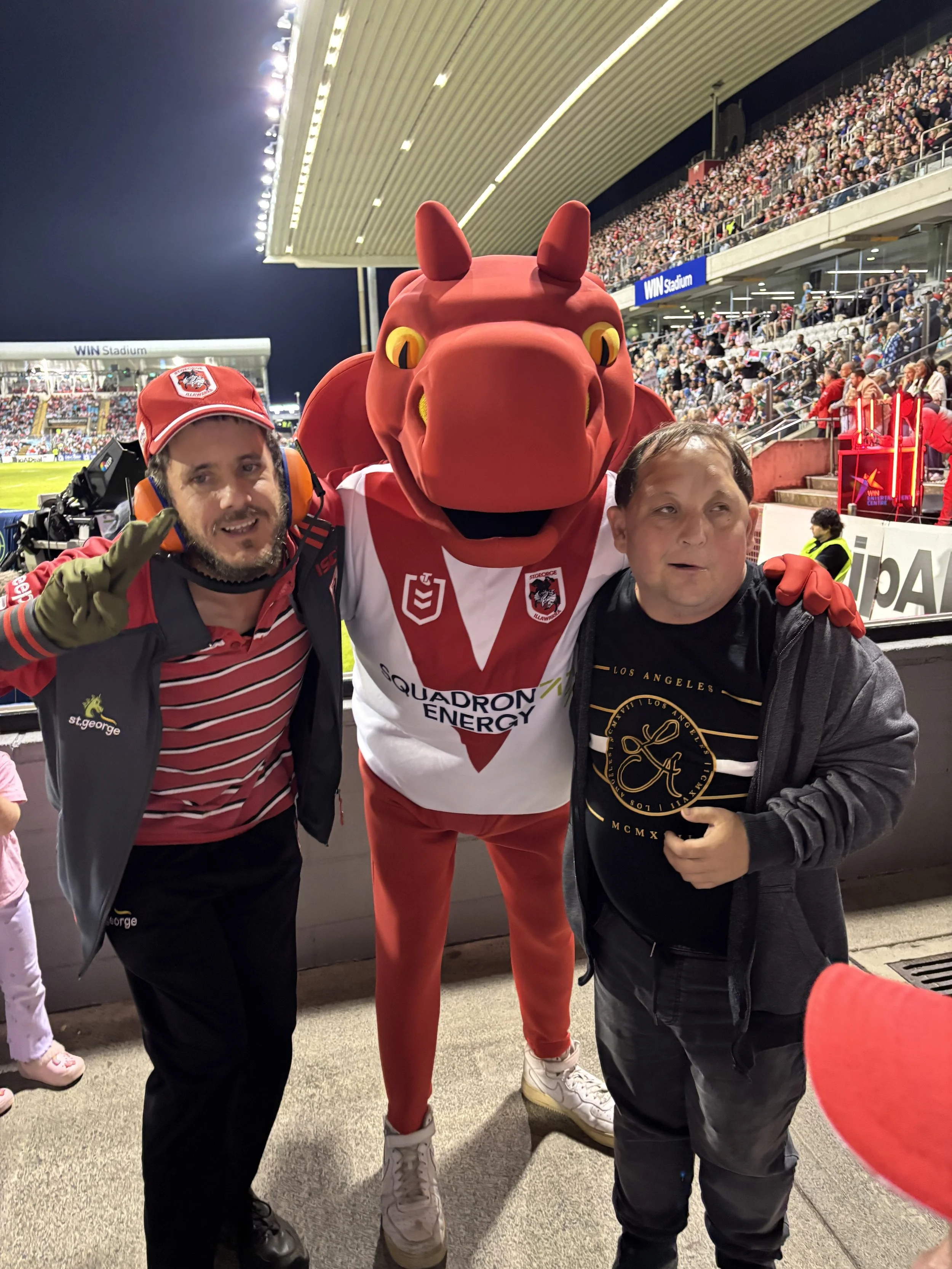 Participants at a Dragon's game with the Dragon's mascot