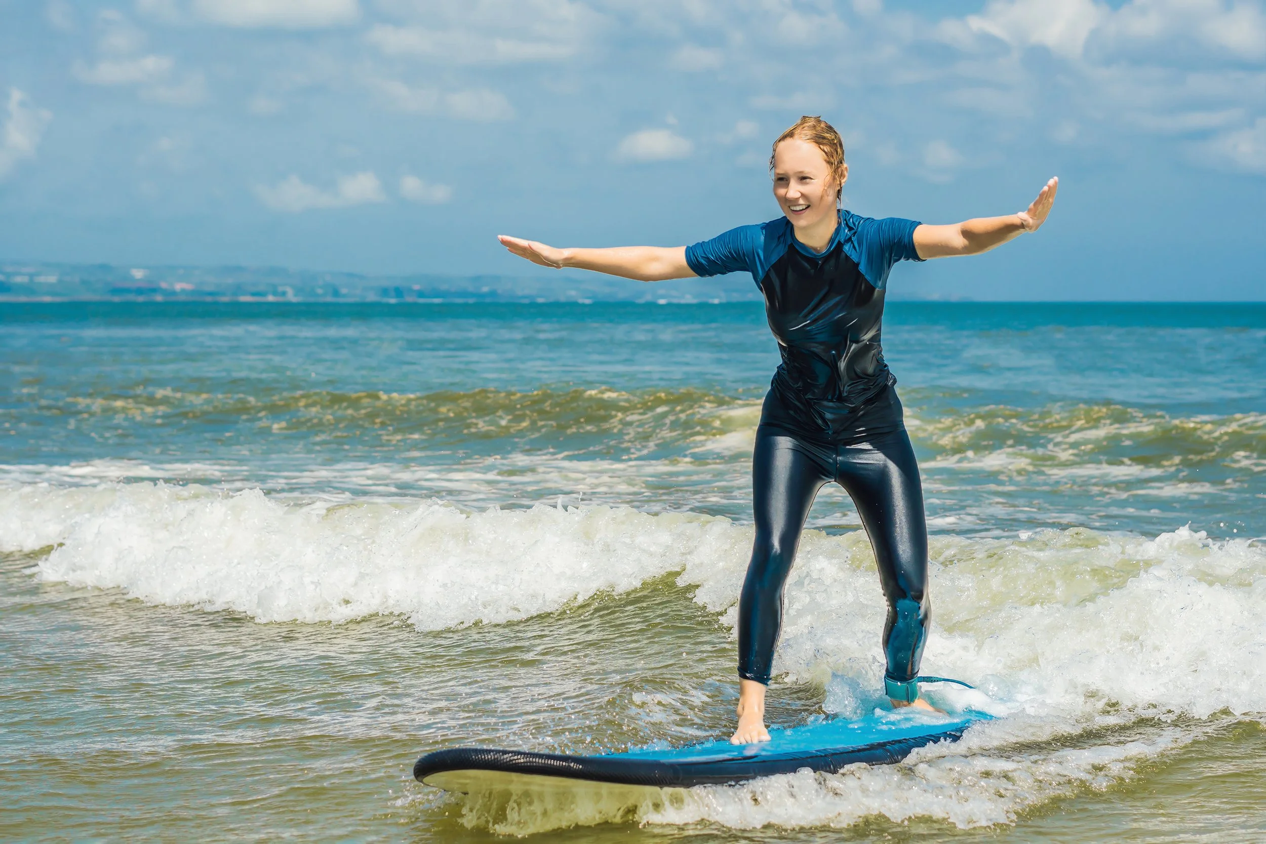 Young woman standing up on blue surfboard in the ocean