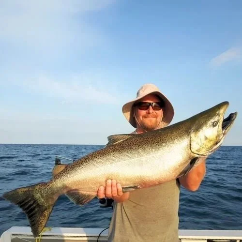 Photo of "Jason" wearing a hat and sunglasses, holding a large fish.