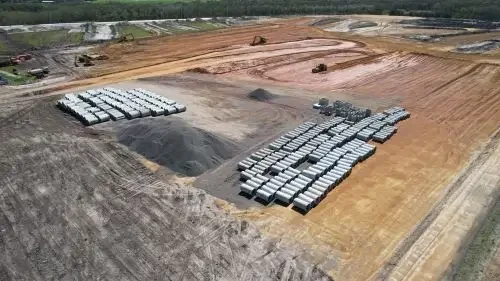 Aerial view of a construction site with parked trucks, piles of dirt, and graded land.