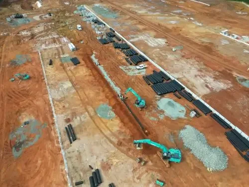 Drone view of underground services installation with excavators, pipework and bulk earthworks on a large civil construction project.