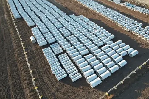 Aerial image of a large amount of pipes sitting on dirt on a construction site.