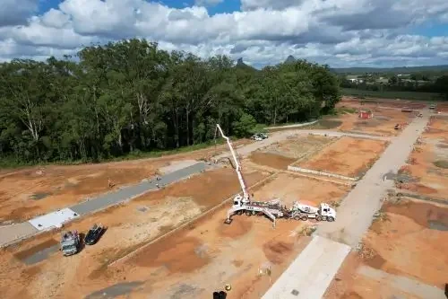 Aerial view of concrete road construction with boom pump and civil works progressing across a residential development site.