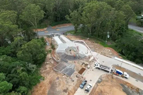 Aerial view of a newly constructed roundabout and road intersection within a residential land development surrounded by bushland.