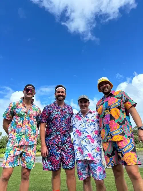 Four men standing together smiling with colourful clothes on.