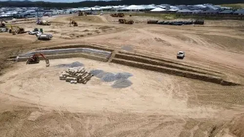 Construction site with excavators, rocks, and gravel, surrounded by dirt and machinery.