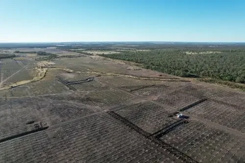 Aerial view of a large solar farm under construction with rows of solar panel foundations across a rural landscape.