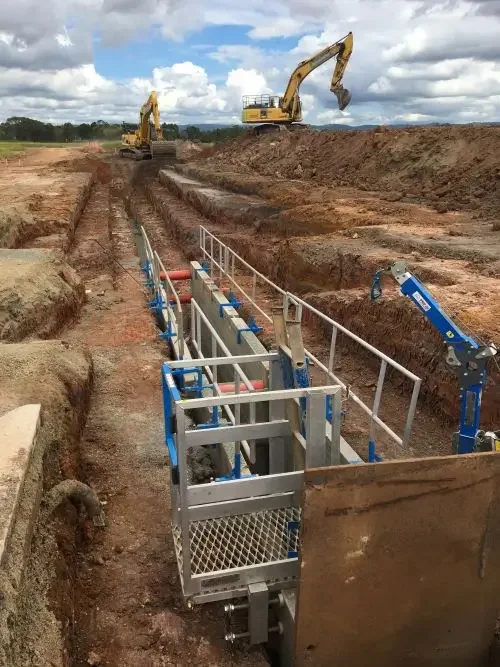 Construction crew installs large underground water infrastructure and valve structures within a deep excavated trench.