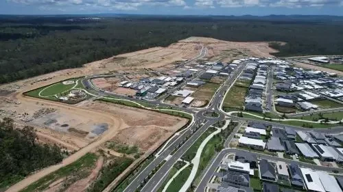 Aerial view of Everleigh Precinct masterplanned community surrounded by undeveloped land, with roads, houses, and buildings under construction.