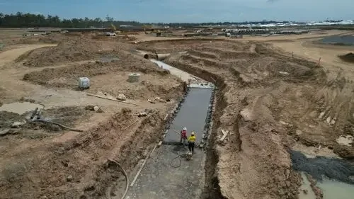 Construction workers building a road in a large excavation site.