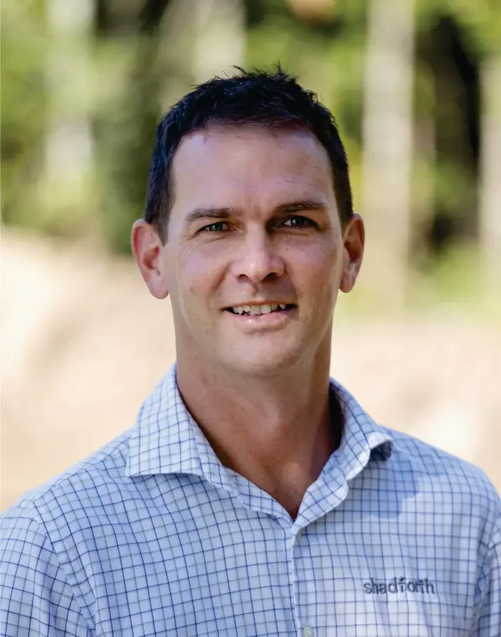 Chief Operating Officer Jeremy Linton wearing a checkered shirt outdoors with trees in the background.
