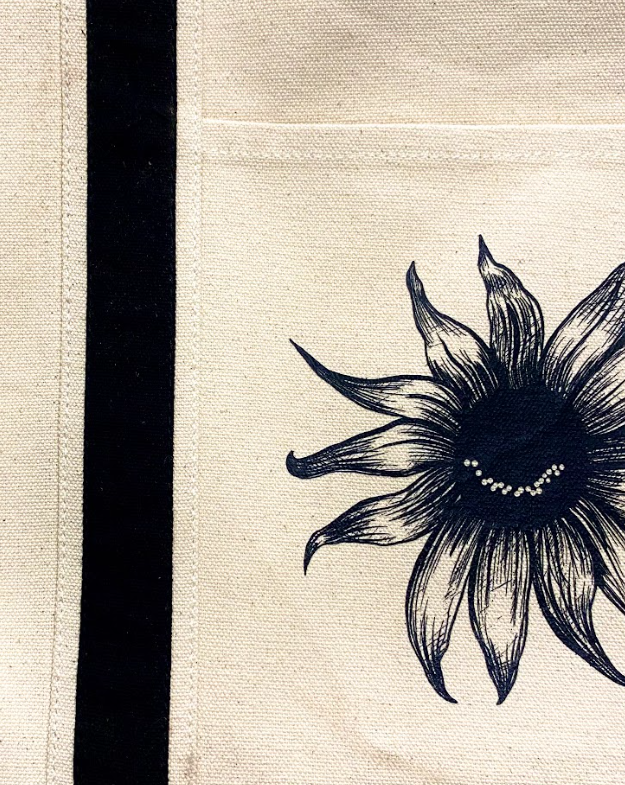 Oversized cotton tote featuring a smiling sunflower graphic on the front.