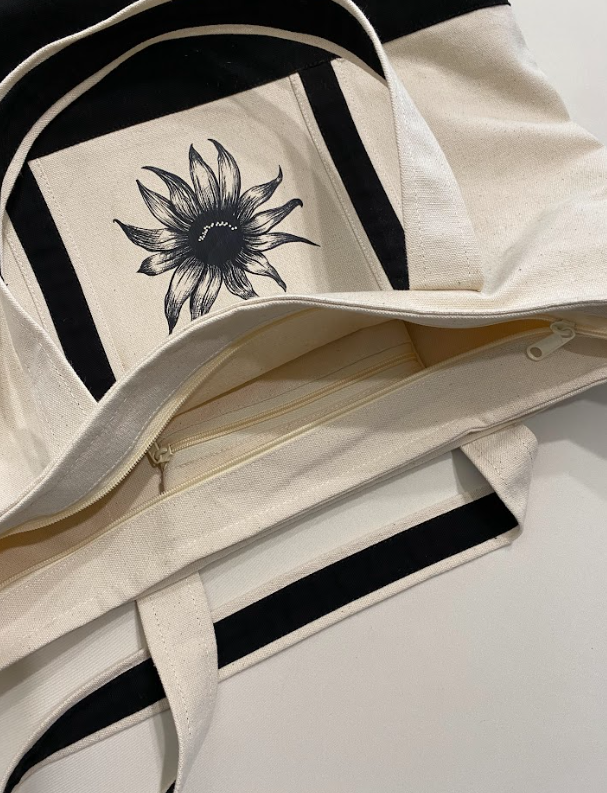 Oversized cotton tote featuring a smiling sunflower graphic on the front.
