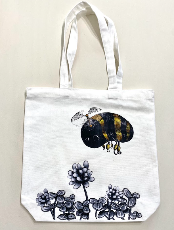 Reusable white grocery tote bags featuring multiple designs, showing the flying bean artwork.