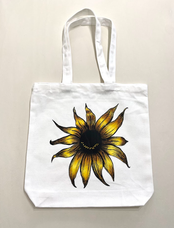 Reusable white grocery tote bags featuring multiple designs, showing a smiling sunflower.