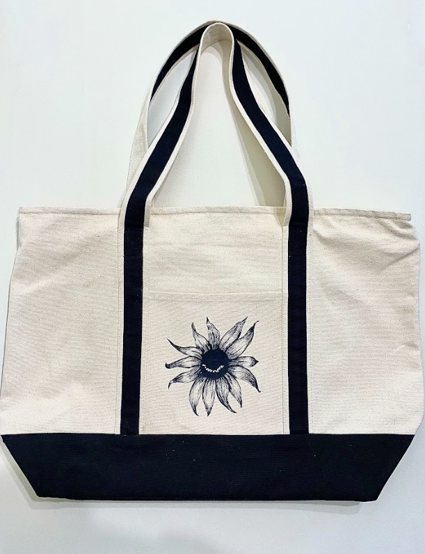 Oversized cotton tote featuring a smiling sunflower graphic on the front.