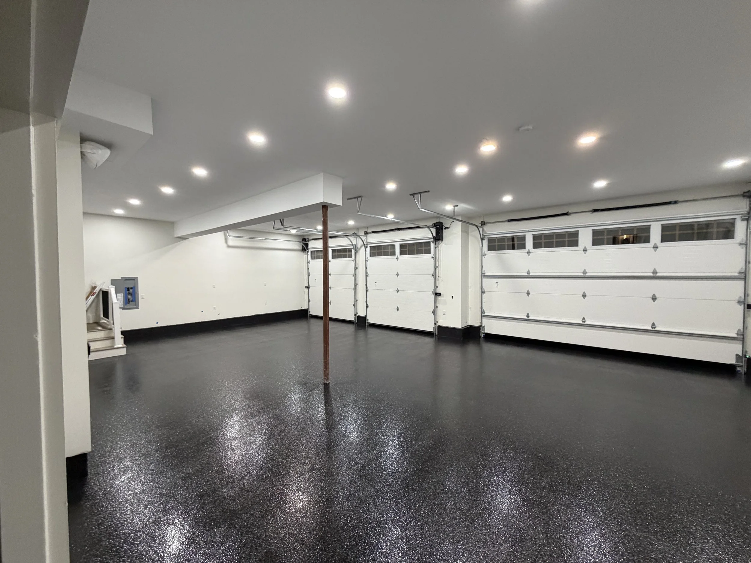 Display of various speckled epoxy floor coatings samples in front of a black wall with a sign for Elev8 Epoxy, including a color swatch board and a blue sample in the center.