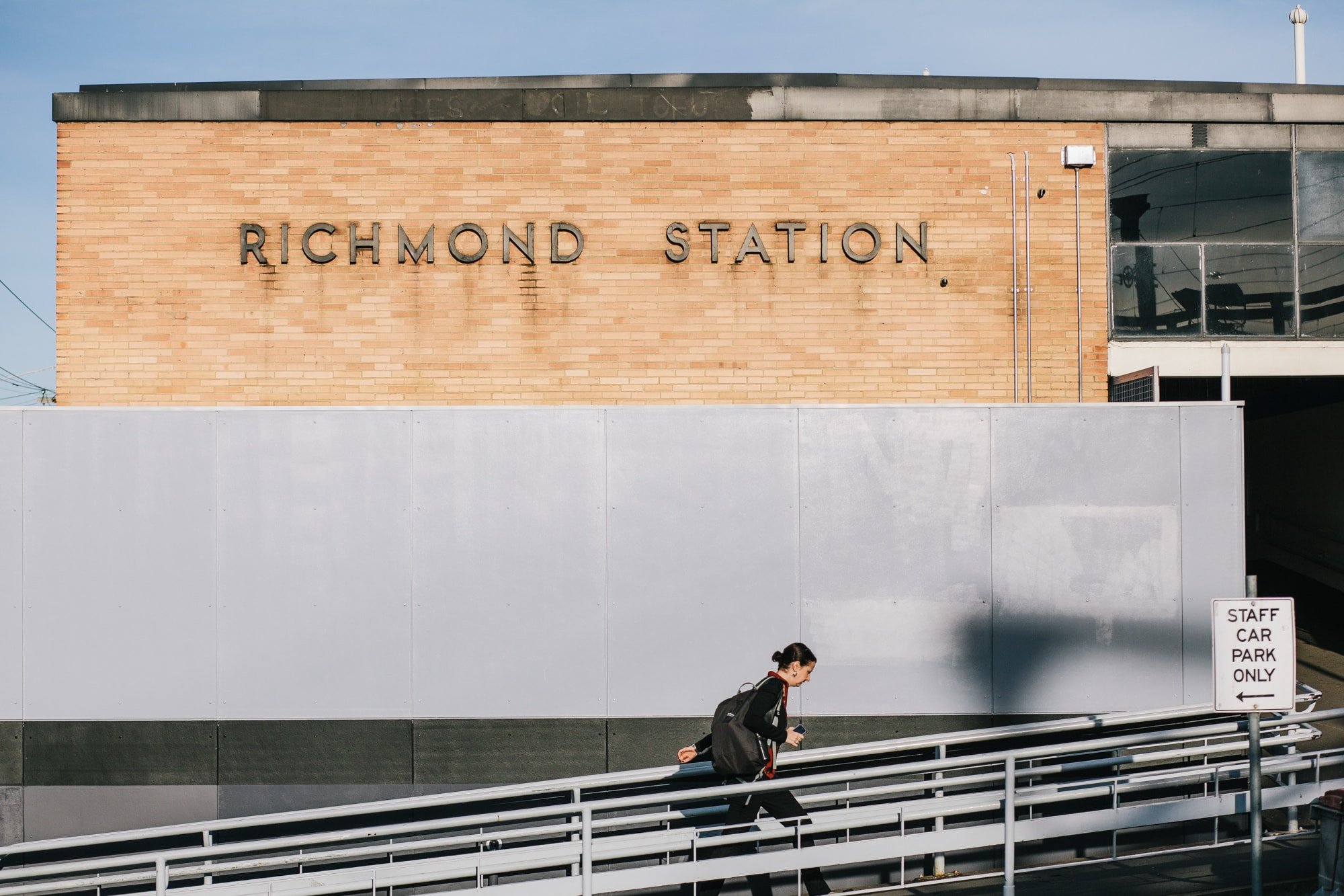 A woman walking the ramp near Richmond Station, a brick building with the station's name on it.