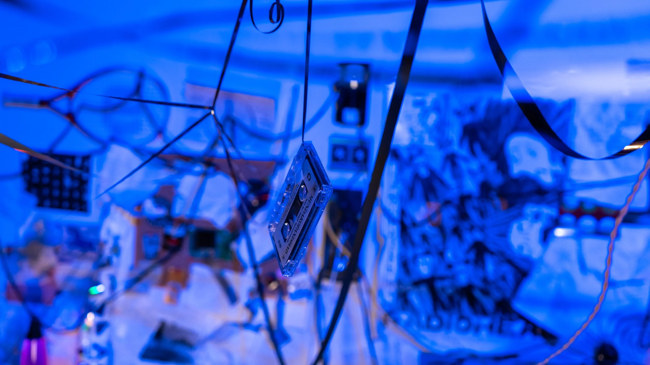 A tangled mess of wires and electronic components illuminated in blue light.